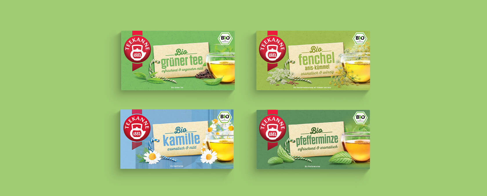 Vier bunte Teekanne-Bioteedosen - Grüner Tee, Fenchel, Kamille, Pfefferminze - auf grünem Hintergrund.
