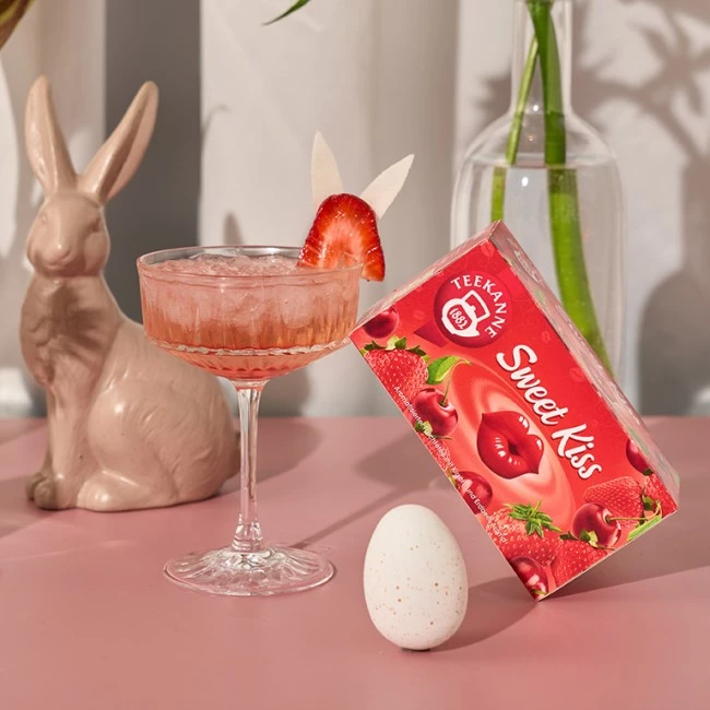 Cocktail mit Erdbeergarnitur, Keramikhase, gesprenkeltem Ei, Sweet Kiss-Teebox und Blumenvase.