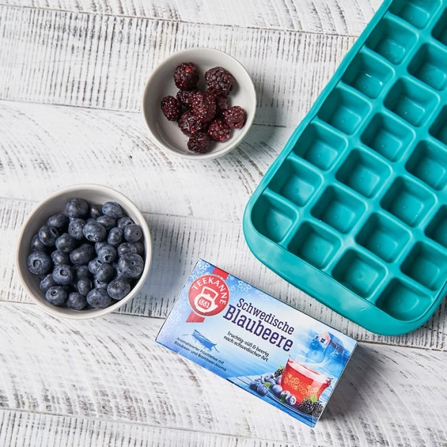 Eiswürfelschale, Schwedische Blaubeere-Box, Blaubeeren und Himbeeren auf weißer Holzoberfläche.