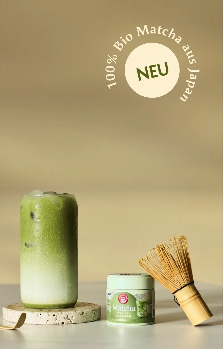Eisgekühlter Matcha-Latte mit einer Matcha-Dose von TEEKANNE mit der Aufschrift „100 % Bio-Matcha aus Japan“, einem Bambus-Schneebesen und einem „NEU“-Etikett.