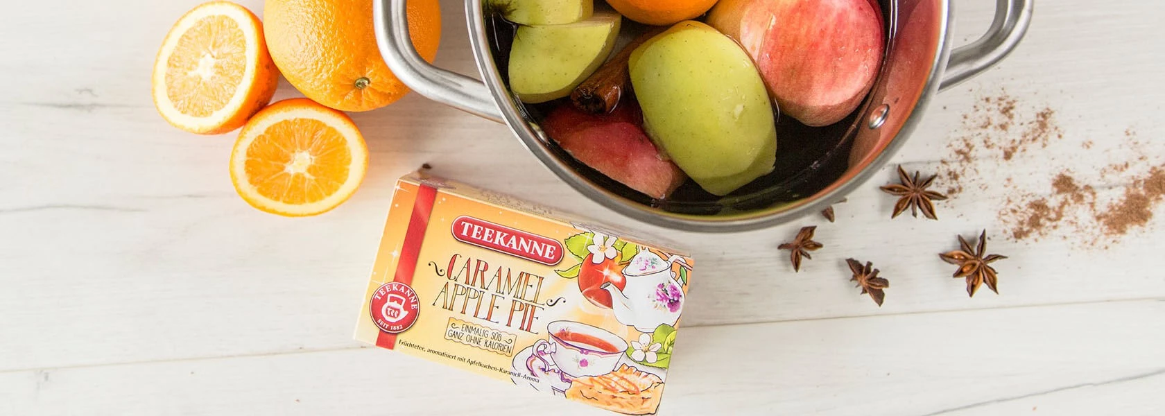 Teekanne Caramel Apple Pie Tee, Äpfel, Orangen, Sternanis und Zimt auf Weiß.