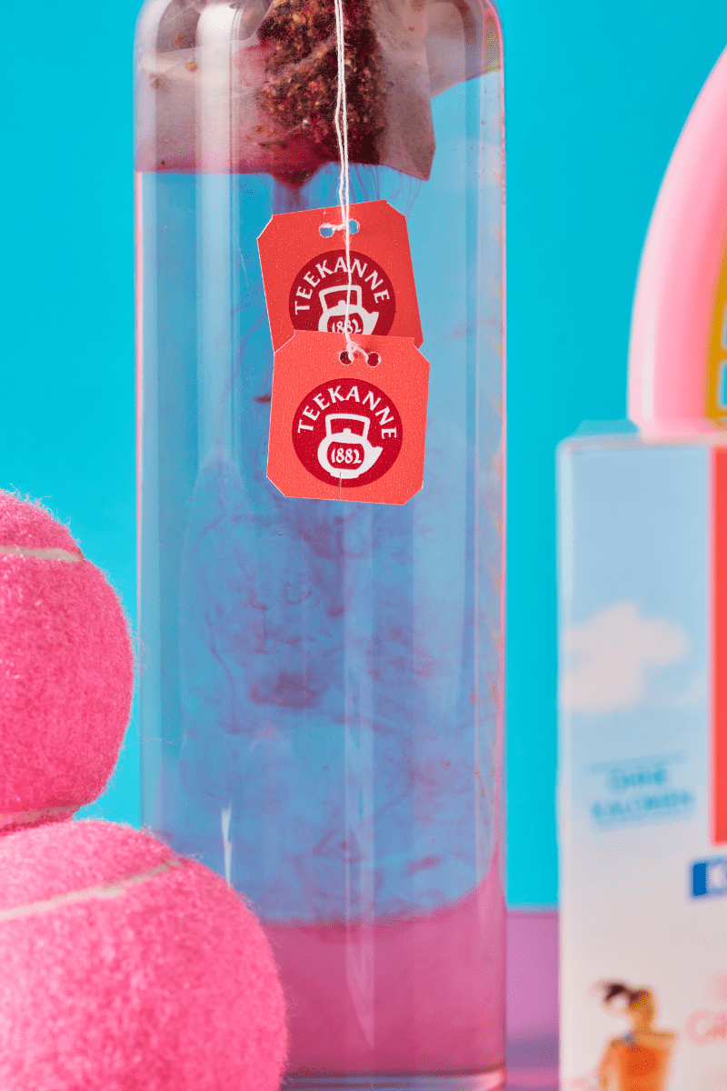 Eine Getränkeflasche mit Wasser, darin zwei Beutel von "frio Sport Fit Grapefruit-Zitrone" zum kalt Aufgießen. Die Farbe des Tees diffundiert ins Wasser.