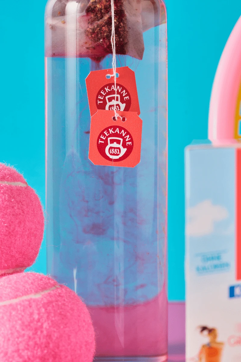 Eine Getränkeflasche mit Wasser, darin zwei Beutel von "frio Sport Fit Grapefruit-Zitrone" zum kalt Aufgießen. Die Farbe des Tees diffundiert ins Wasser.