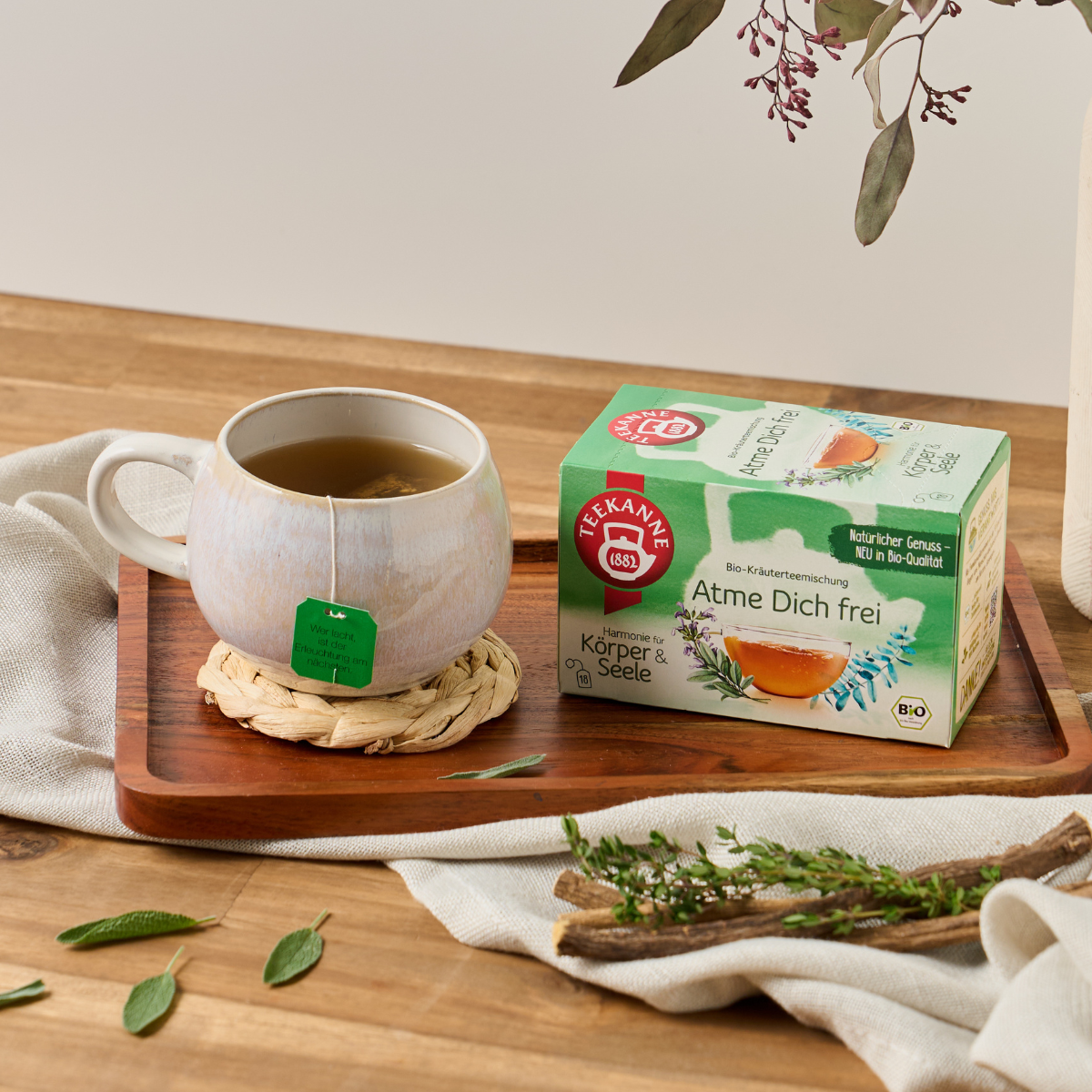 Teepackung und Teetasse auf Holzbrett.