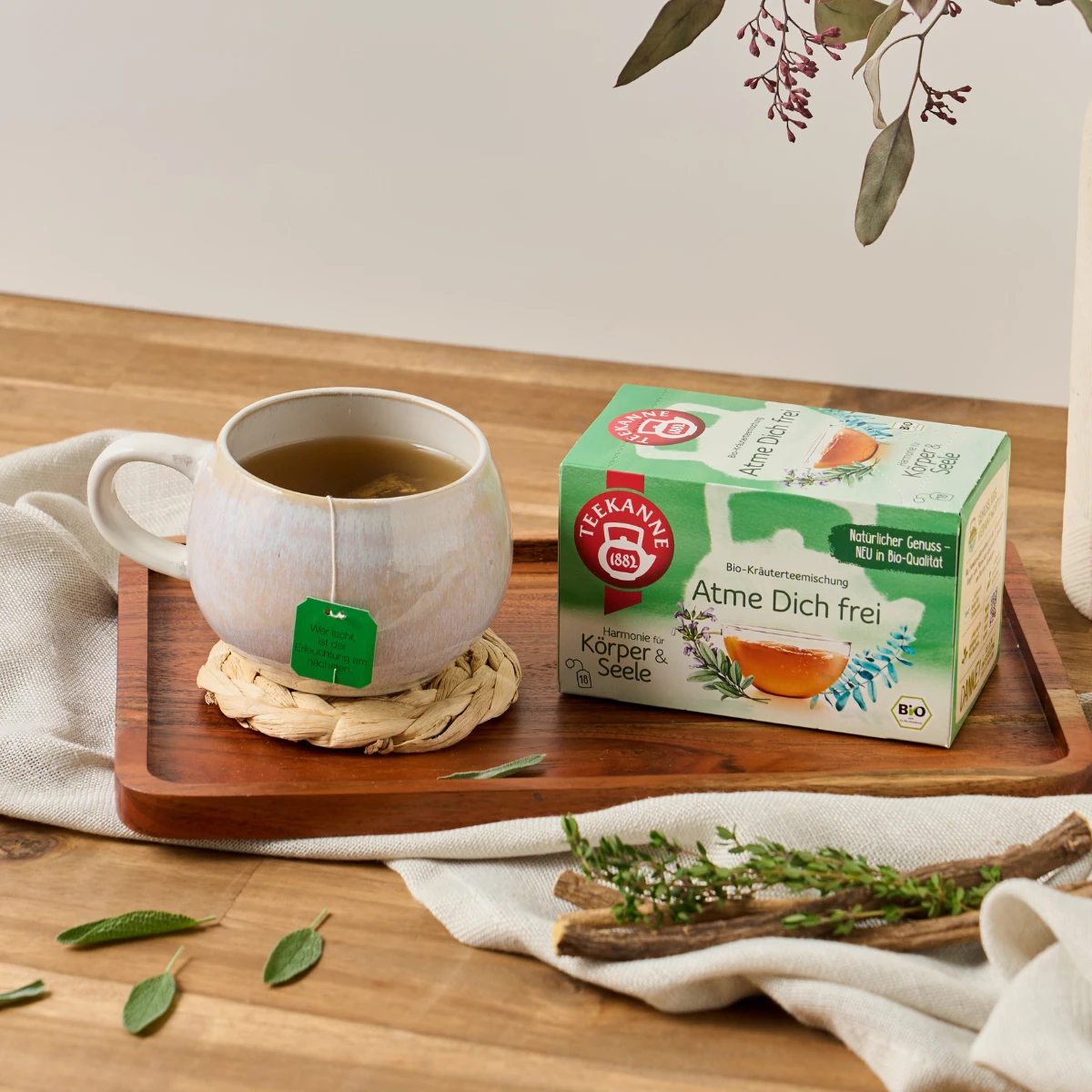 Teepackung und Teetasse auf Holzbrett.