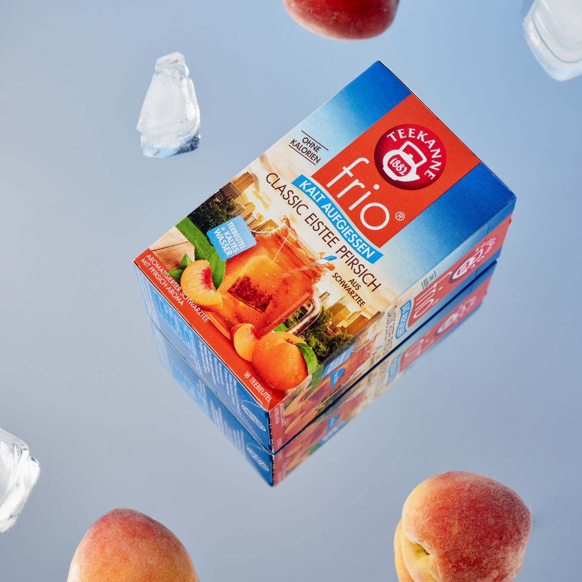 Eine Schachtel Frio Mix & Match Eistee mit klassischem Pfirsichgeschmack steht mit Eiswürfeln und ganzen Pfirsichen auf einer reflektierenden Oberfläche – ideal für Fans von Früchtetees und perfekt zum Kaltaufbrühen. Mix & Match mit deinen Lieblingssorten