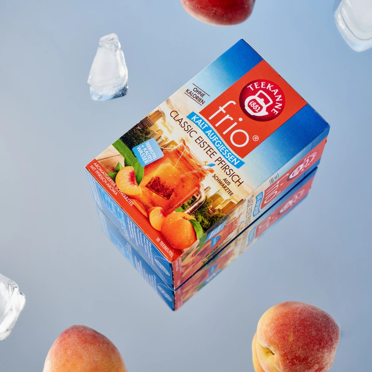 Eine Schachtel Frio Mix & Match Eistee mit klassischem Pfirsichgeschmack steht mit Eiswürfeln und ganzen Pfirsichen auf einer reflektierenden Oberfläche – ideal für Fans von Früchtetees und perfekt zum Kaltaufbrühen. Mix & Match mit deinen Lieblingssorten