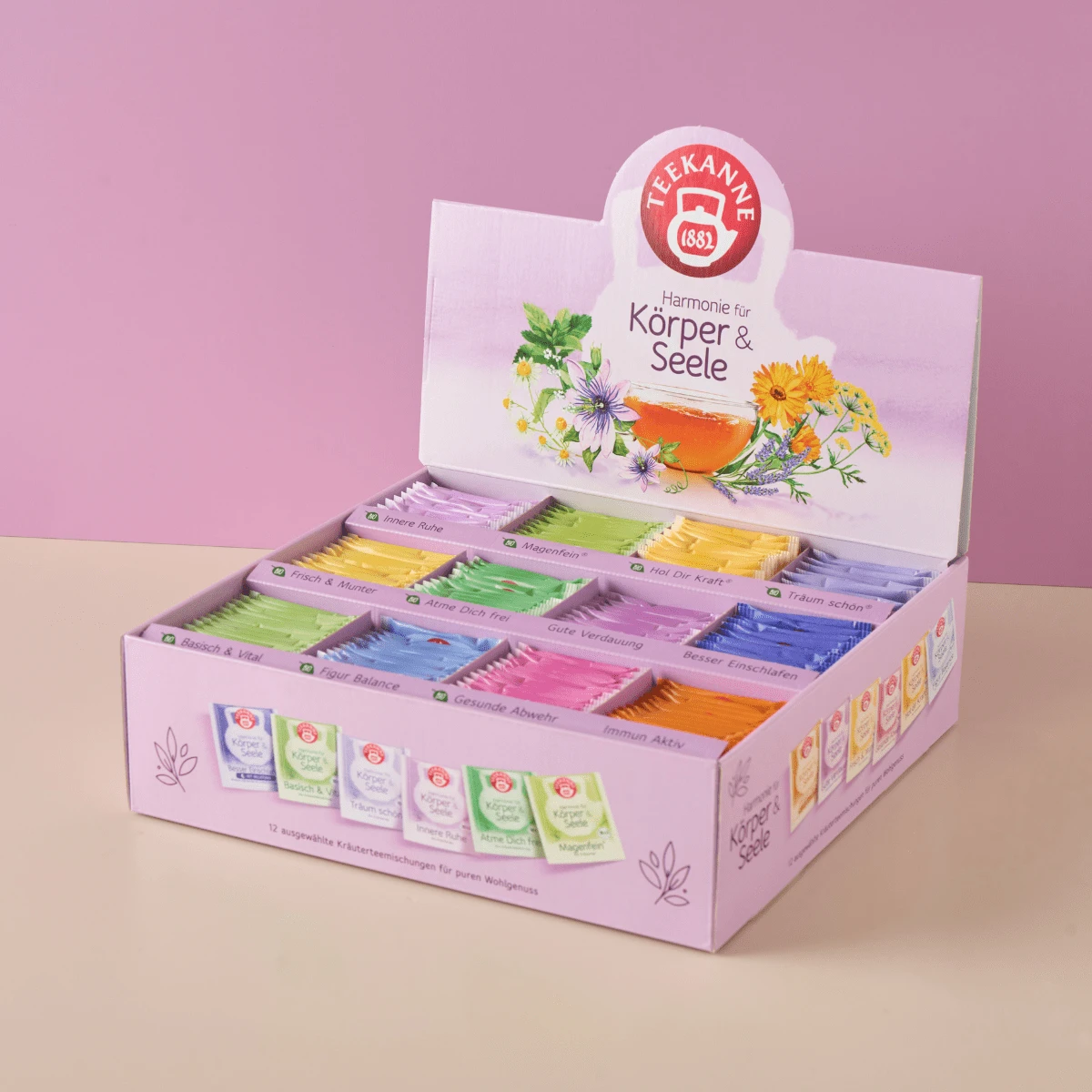 Eine pastellfarbene Wohlfühl-Collection Box Geschenkset (180 Beutel) von Teekanne Tees mit der Aufschrift Harmonie für Körper & Seele, mit jeder Sorte in einer einzigartigen farbigen Verpackung und floralen Mustern, wird vor einem lila Hintergrund präsent
