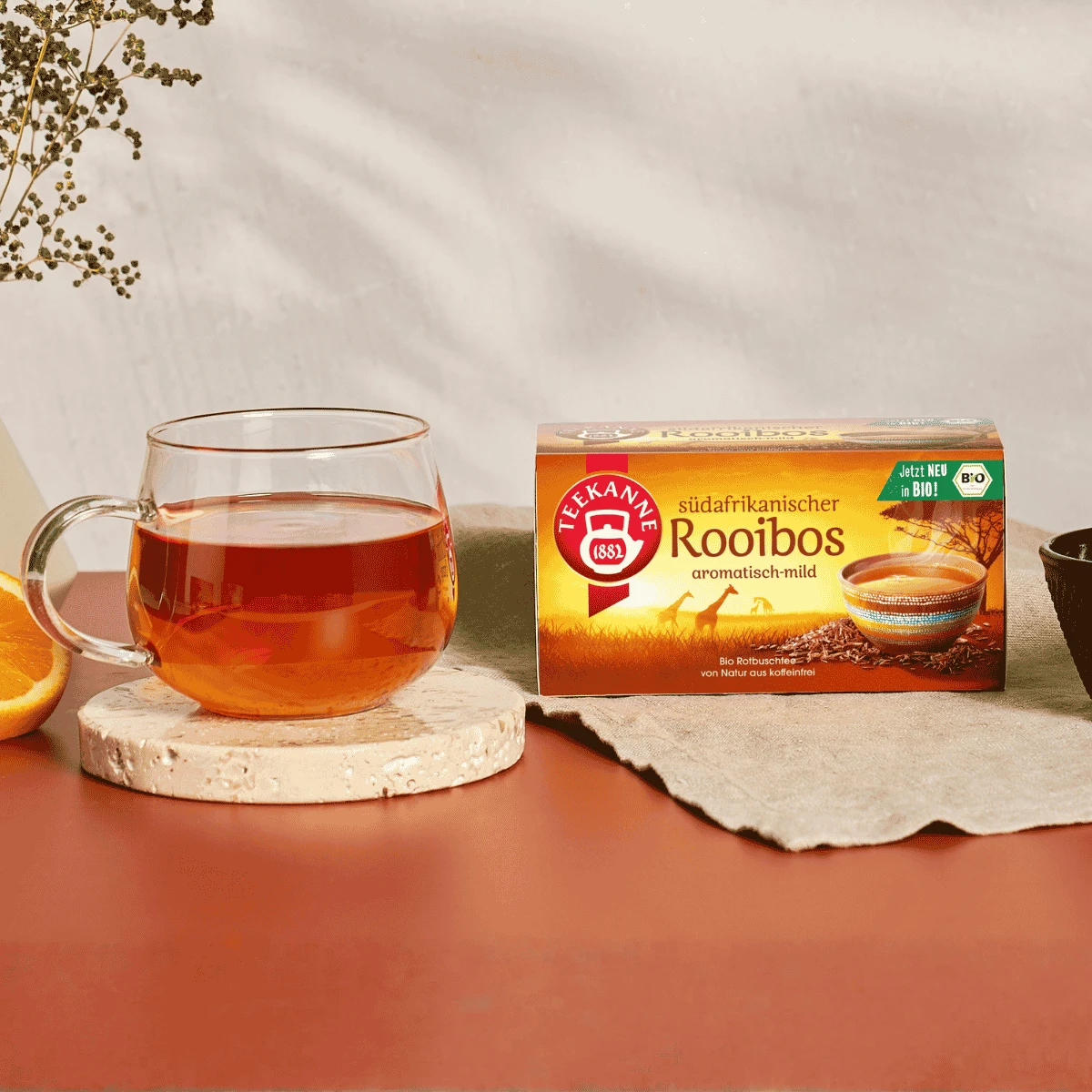 Ein Glas eisgekühlter Bio-Matcha-Latte mit deutlich erkennbaren grünen und weißen Schichten steht auf einem Holztablett neben einem kleinen Glas mit Bio-Matcha-Pulver.